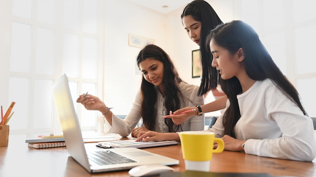 Estudiantes universitarios dan clases particulares juntos mientras están sentados frente a una computadora portátil