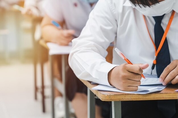 Estudiantes universitarios escribiendo en exámenes finales en el aula de forma concentrada