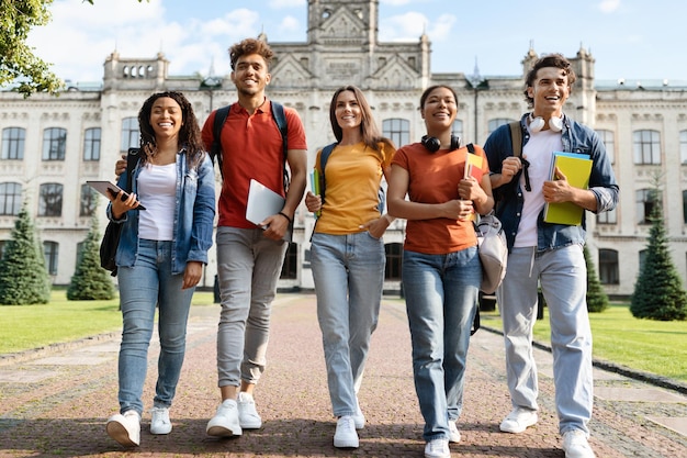 Estudiantes universitarios grupo de jóvenes multiétnicos caminando juntos al aire libre