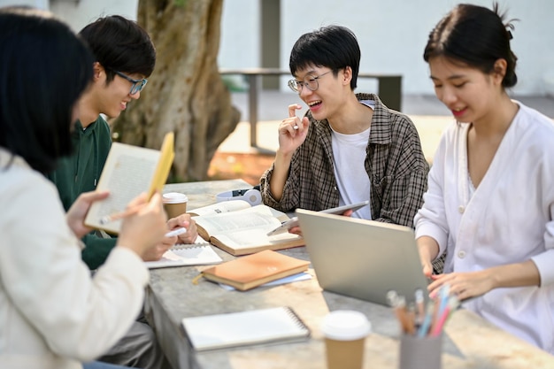 Estudiantes universitarios masculinos asiáticos felices enseñando economía a sus amigos en un parque del campus