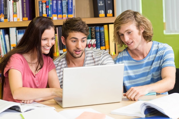 Estudiantes universitarios que usan la computadora portátil en biblioteca