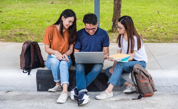 Estudiantes varones están abriendo una computadora para una amiga, concepto de educación