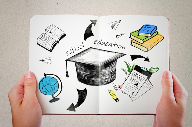 Estudiar en la educación universitaria y el concepto de conocimiento con libros de birrete dibujados a mano globo y flechas en hojas de cuaderno blancas sostenidas por manos humanas
