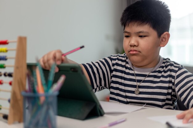 Estudio de clase de aprendizaje de niños asiáticos lindos en línea con videollamada desde tableta en casa Concepto de distanciamiento social