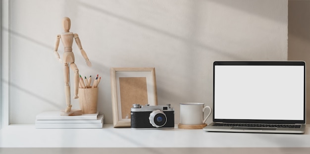 Estúdio criativo de fotógrafo com laptop de tela em branco e acessórios de escritório