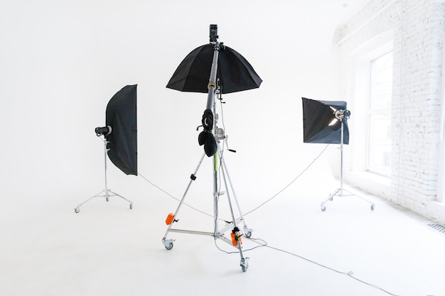 Estúdio de fotografia vazio com equipamento de iluminação. interior do local de trabalho do fotógrafo com conjunto de ferramentas profissionais. luz do flash, cenas de fundo branco prontas para fotografia em estúdio. estúdio de fotógrafo moderno