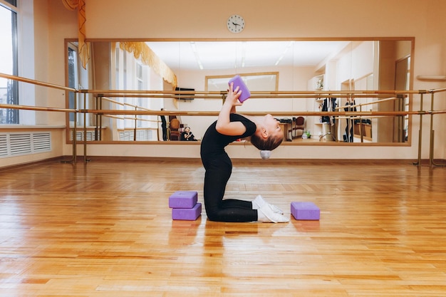 Estúdio de ginasta de garota. pequena ginasta realiza um exercício no chão. O conceito de esportes, ginástica, fitness.