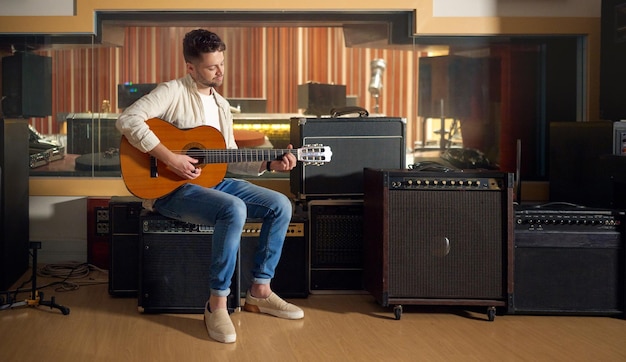 Estúdio de gravação acústico e homem tocando violão para produção musical ou praticando para uma performance Artista guitarrista e cara dedilhando as cordas de um instrumento musical para uma trilha sonora