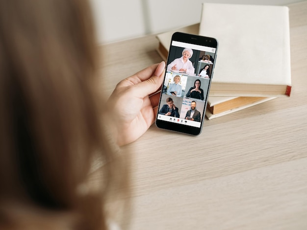 Estudio digital Clase de video móvil Tecnología de educación moderna Entrenador de negocios femenino senior que enseña a los estudiantes en la pantalla del teléfono inteligente en el lugar de trabajo con libros