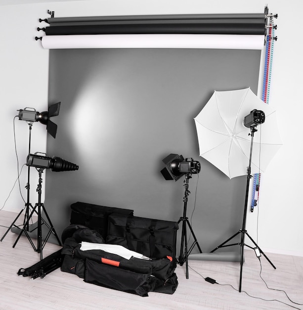 Estudio fotográfico vacío con bolsas de equipos de iluminación y telón de fondo.