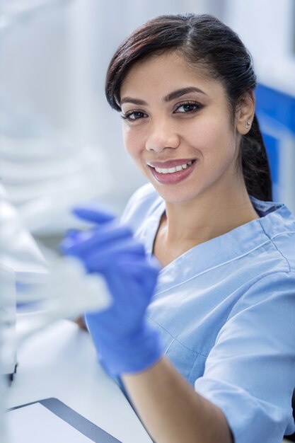 Foto estudio del genoma. feliz agradable médico agradable sonriendo y mirando el modelo de adn mientras realiza una investigación genética