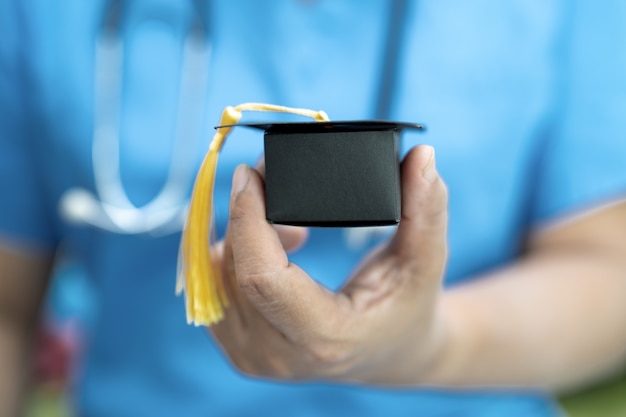 Estudio médico asiático aprende con sombrero de graduación en la sala del hospital