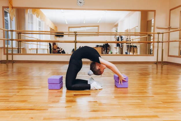 Estudio de niña gimnasta. pequeña gimnasta realiza un ejercicio en el suelo. El concepto de deportes, gimnasia, fitness.