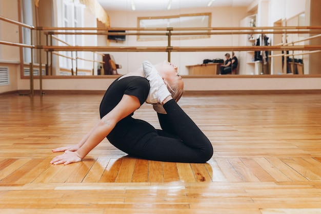 Estudio de niña gimnasta. pequeña gimnasta realiza un ejercicio en el suelo. El concepto de deportes, gimnasia, fitness.