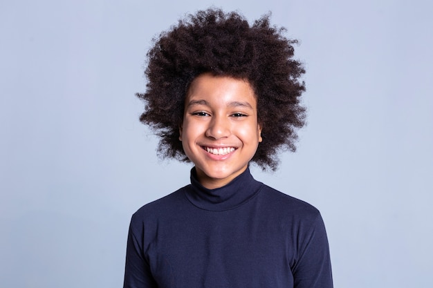 Estúdio profissional. Muito jovem com um sorriso largo, penteado africano e mostrando emoções na câmera