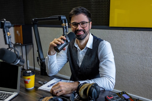 En el estudio de radio. Hombre moreno barbudo que mira la cámara