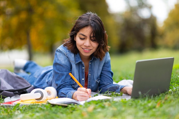 Estudio remoto joven mujer árabe con portátil preparándose para el examen al aire libre