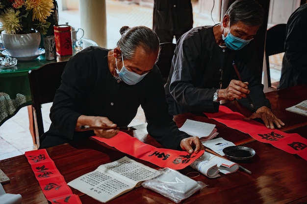 Foto estudioso vietnamita escreve caligrafia no festival de caligrafia long son é uma tradição popular durante o feriado de tet escrevendo dísticos para o festival da primavera do ano novo