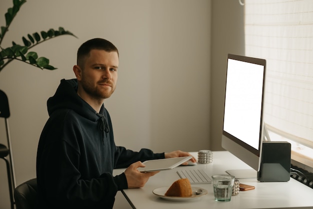 Estudo remoto online. um aluno feliz estuda remotamente usando um computador multifuncional. um colega estudando com um tablet em casa.