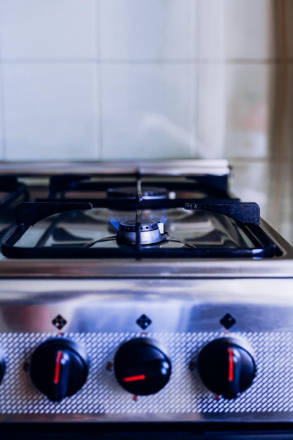 Estufa de cocina a gas con una llama azul ardiente y perillas de control de potencia de fuego