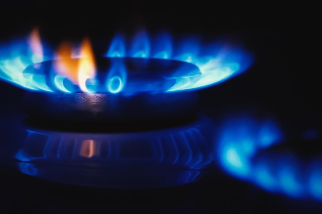 Foto estufa de gas cocina llama azul en los anillos de gas oscuro ardiendo closeup