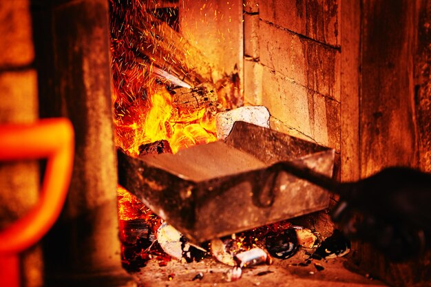 Una estufa en un restaurante con carbones encendidos arroja carbones al horno con carbones picados