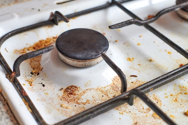 Estufa sucia con restos de comida. Estufa de cocina de gas sucia con manchas de grasa, manchas de grasa viejas, manchas de freír y salpicaduras de aceite.