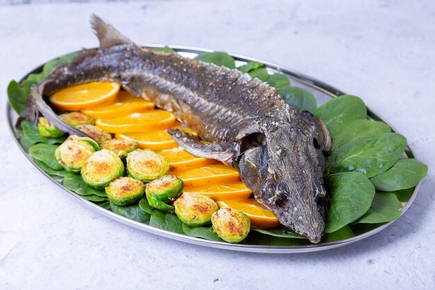 Esturión al horno (esturión) con espinacas, naranjas y coles de Bruselas. Cocina rusa. De cerca.