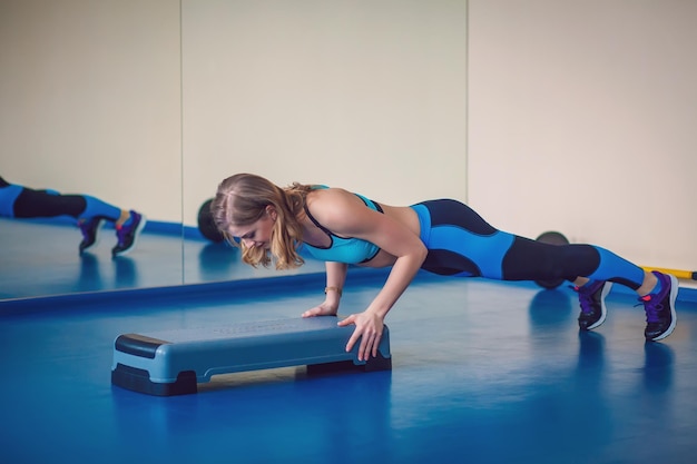 Etapa de fitness, treinamento, aeróbica, conceito de esporte - treinador de mulher atlética na etapa fazendo aula de aeróbica com steppers. mulher fitness com plataforma de passo fazendo exercícios no ginásio. concepção do esporte.