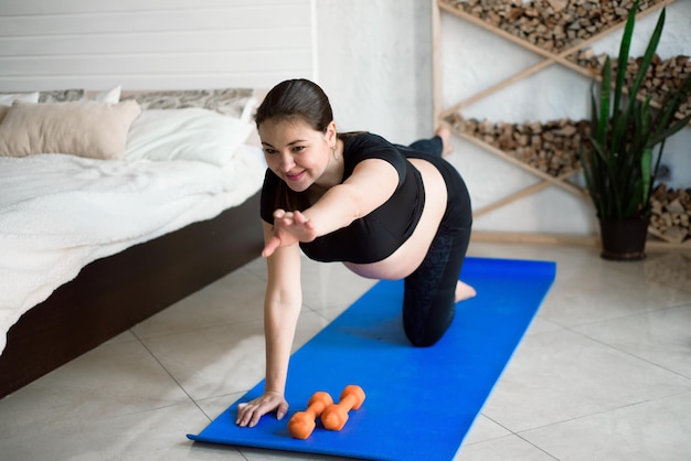 Etapa del embarazo Bonita mujer embarazada posando y probando yoga