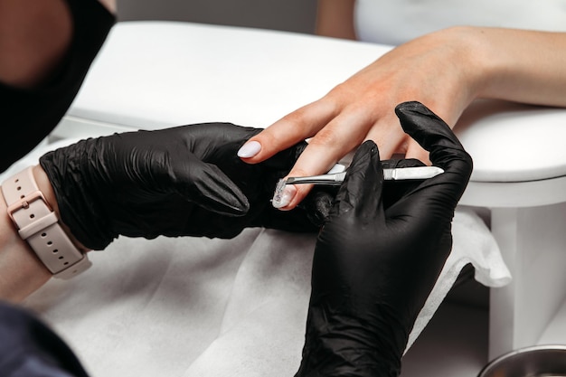 Etapa de manicura pegando pegatinas en la uña Trabajar en un salón de belleza manicura pequeña empresa