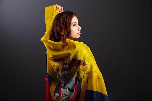 Ethnische ecuadorianische Dame mit der wehenden ecuadorianischen Flagge isoliert auf grauem Hintergrund