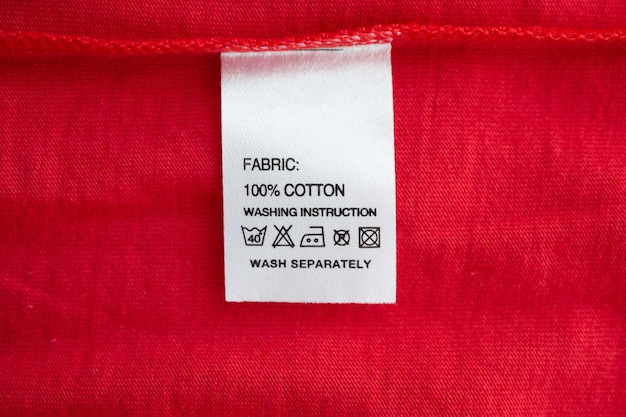 Foto etiqueta branca de instruções de lavagem de roupas para lavar roupas em camisa de algodão vermelha