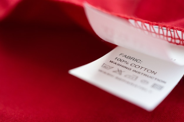 Etiqueta branca de instruções de lavagem de roupas para lavar roupas em camisa de algodão vermelha