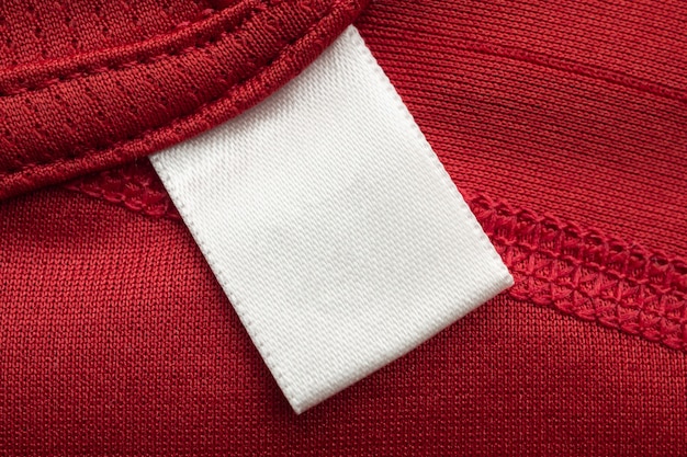 Etiqueta branca em branco para roupas de lavanderia em fundo de camisa esporte de poliéster vermelho