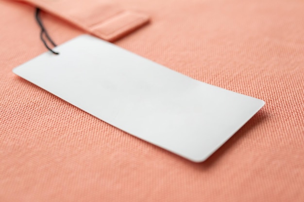 Foto etiqueta de etiqueta de roupa branca em branco no fundo de textura de tecido rosa