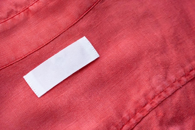 Etiqueta de etiqueta de roupa branca em branco sobre fundo de textura de tecido de camisa de linho vermelho