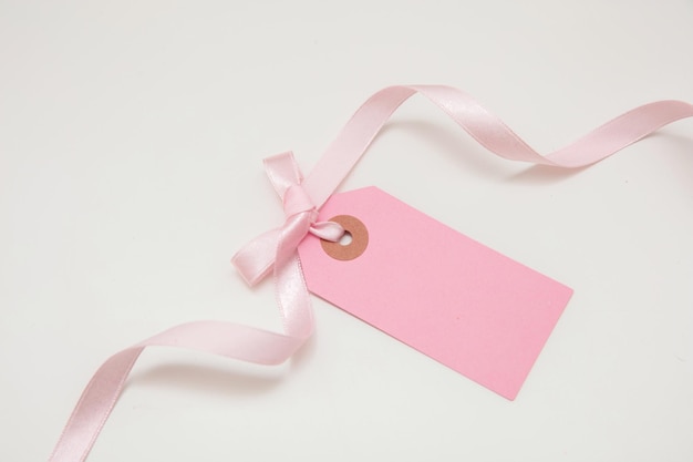 Etiqueta de preço rosa em branco isolada no fundo branco Cartão de presente vazio de cor pastel e laço de fita encaracolado