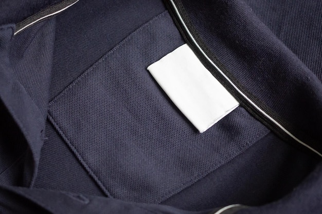 Etiqueta de roupa de lavagem branca em branco em fundo de textura de tecido de camisa preta