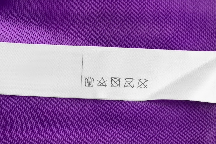 Foto etiqueta de roupas de instruções de cuidados em fundo têxtil roxo