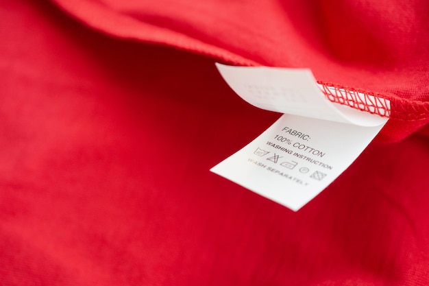 Etiqueta de roupas de instruções de lavagem de roupas brancas na camisa de algodão vermelha