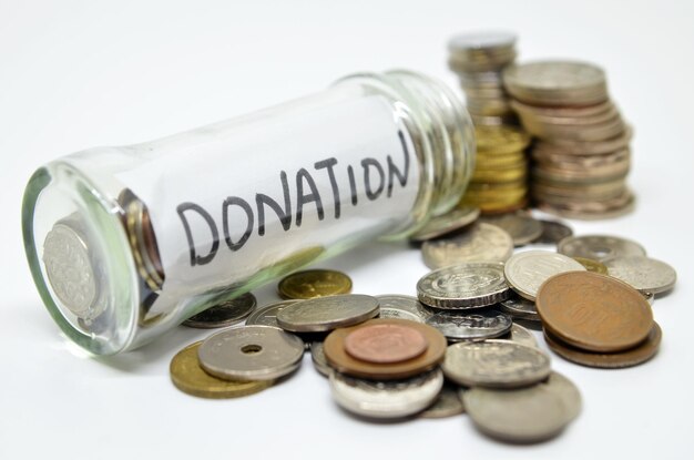 Etiqueta de donación en un frasco de vidrio con monedas derramándose