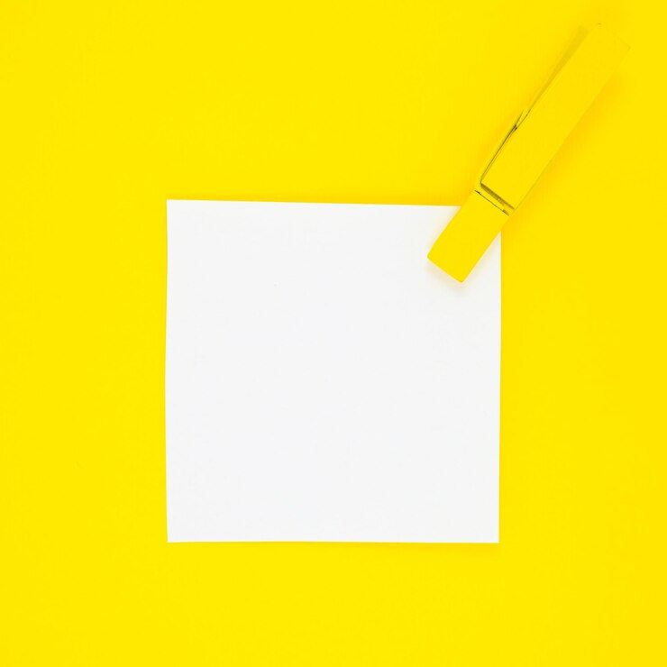 Foto etiqueta engomada de la lista de tareas pendientes en blanco con pinza de madera amarilla. ciérrese para arriba del papel de nota del recordatorio en el fondo amarillo. copie el espacio. minimalismo, fotografía original y creativa.