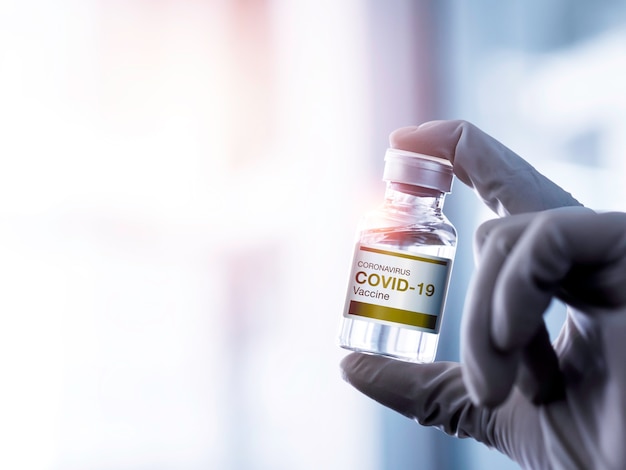 Etiqueta moderna vacuna Covid19 en frasco vial que muestra la mano del científico con guantes en el laboratorio con espacio de copia
