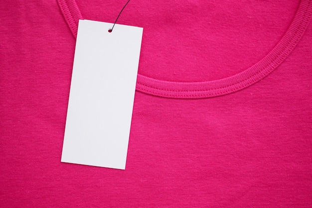 Etiqueta de ropa blanca en blanco en la nueva camisa rosa