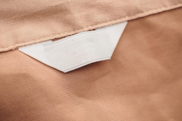 Foto etiqueta de ropa blanca en blanco sobre fondo de textura de tela marrón