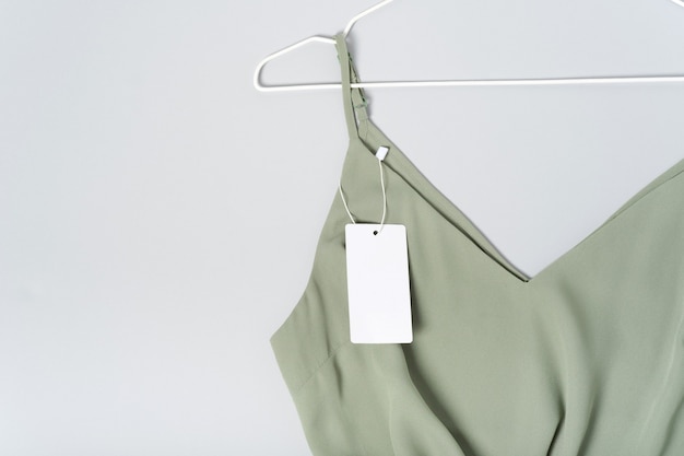 Etiqueta de ropa blanca, plantilla de maqueta de etiqueta en blanco. Sobre una blusa verde caqui de algodón de primera calidad. percha
