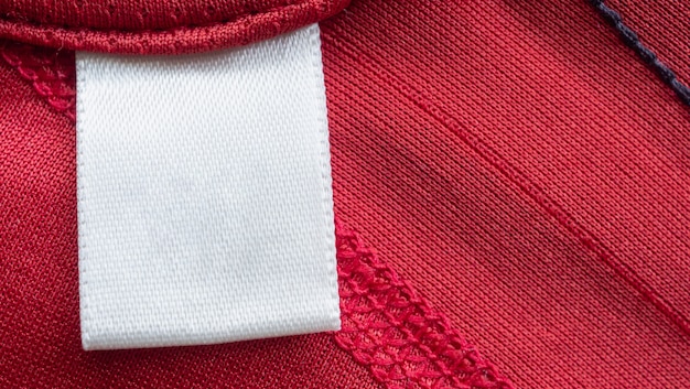 Etiqueta de ropa de cuidado de lavandería en blanco blanco en camisa deportiva de poliéster roja