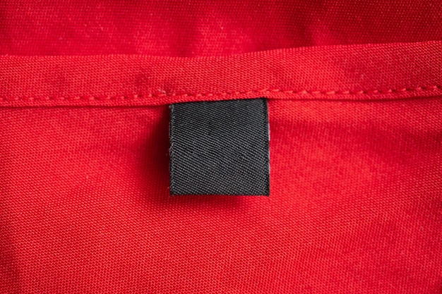 Etiqueta de ropa negra en blanco para el cuidado de la ropa en la textura de la tela de color rojo