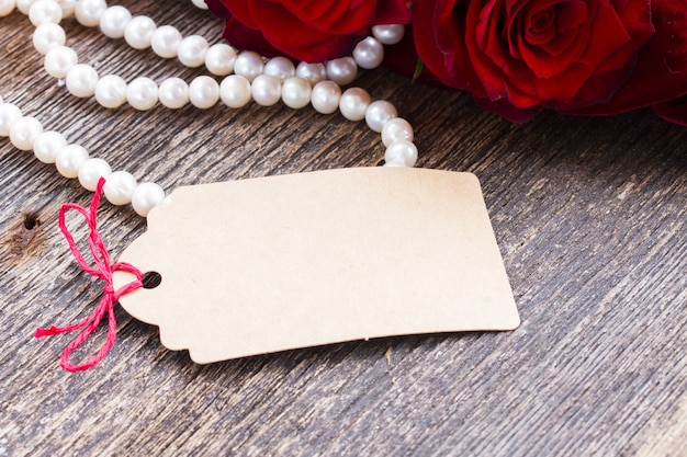 Etiqueta vacía sobre mesa de madera con perlas y joyas